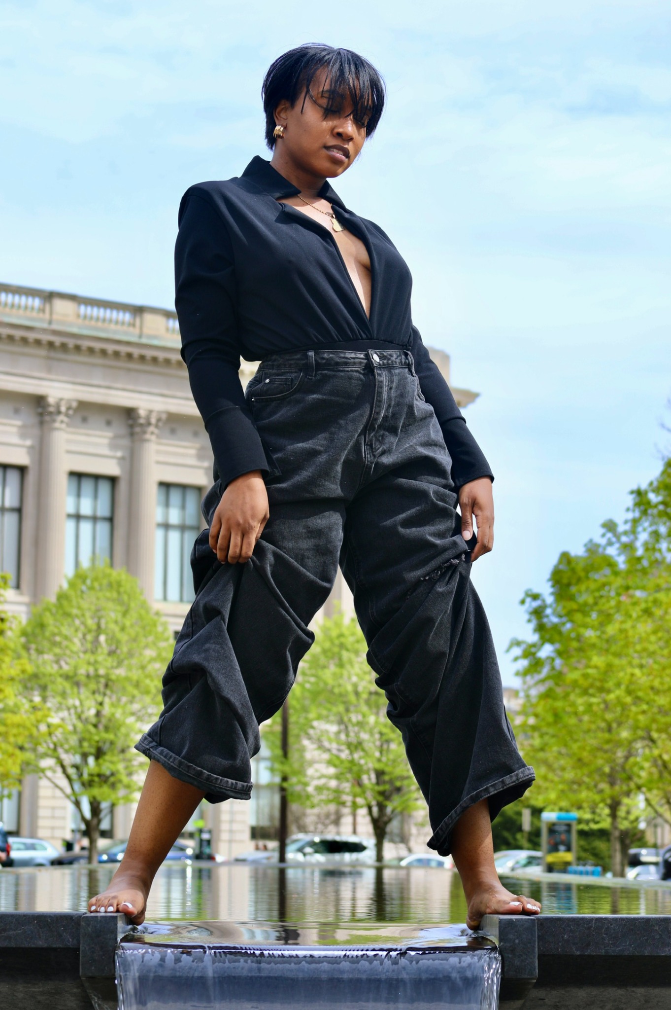 Tiffani Kennard standing at a reflecting pool in black tailoring