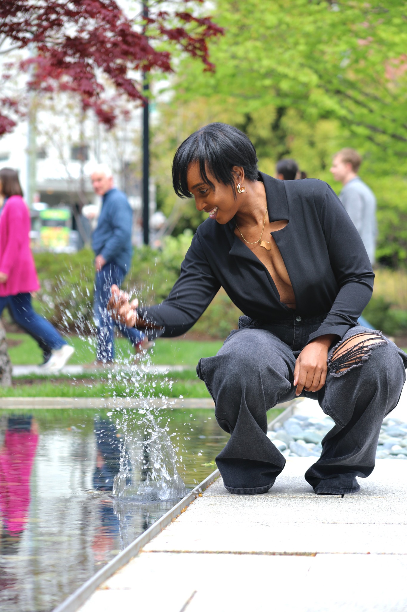Tiffani Kennard smiling and reaching into a reflecting pool